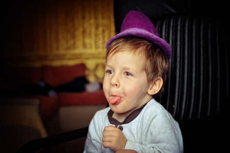 little boy in a purple hat and a white jacket fun grimacingの写真素材