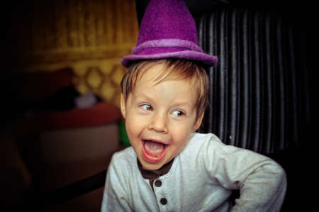 little boy in a purple hat and a white jacket fun grimacingの写真素材