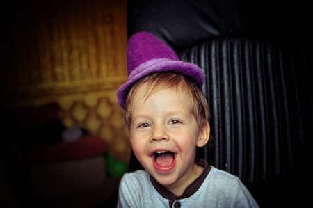 little boy in a purple hat and a white jacket fun grimacingの写真素材