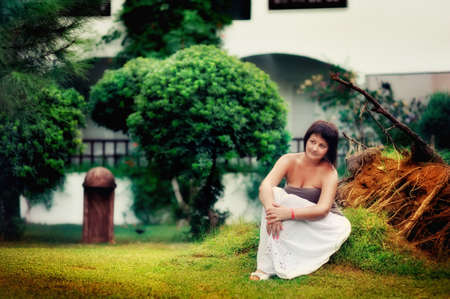 young girl in the park in the summer sitting on the green grassの写真素材