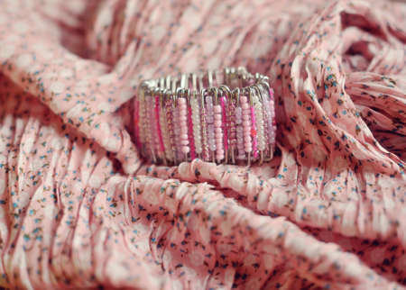 on a pink scarf is feminine bracelet of small colored beadsの写真素材