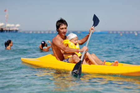 little boy with his father in the yellow boat floating on the seaの写真素材