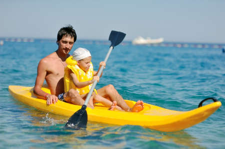 little boy with his father in the yellow boat floating on the seaの写真素材