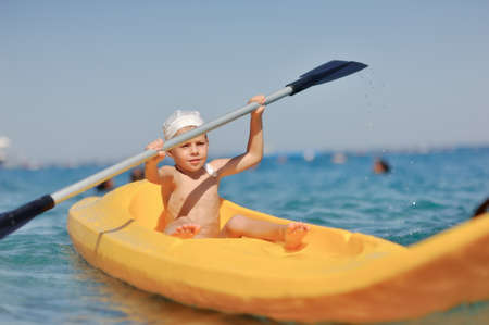 little boy swimming in the yellow boat on the seaの写真素材