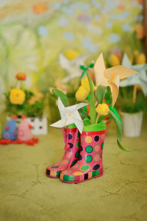 on a green background with flowers rubber boots and paper toysの写真素材