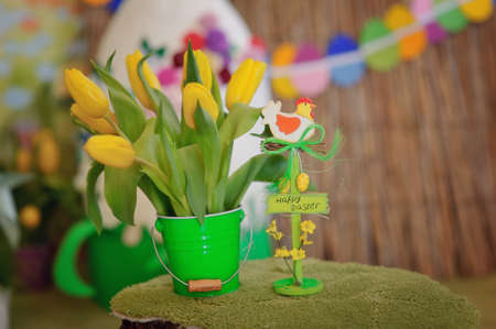 in a green bucket bouquet of yellow tulips and a toy chickenの写真素材