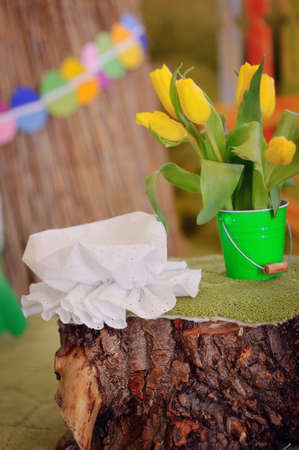 on the stump is a bucket with a bouquet of flowers and a white cap