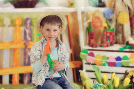 sits a wonderful boy in a straw hat with a chicken and carrotsの写真素材