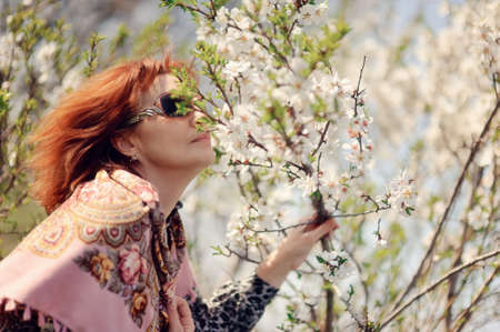 portrait of a girl with glasses on the background of a flowering tree in spring in the gardenの写真素材