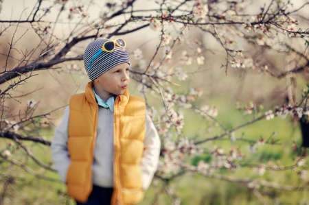 little boy in a yellow jacket and sunglasses in a spring gardenの写真素材