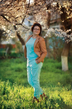 girl in glasses on a background of a blossoming tree in spring in the gardenの写真素材