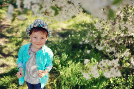 in nature in a lush garden a little boy in a blue shirt and hatの写真素材