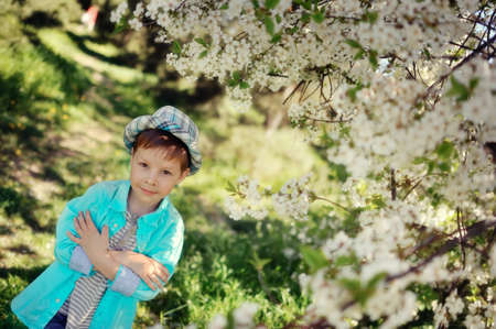 in nature in a lush garden a little boy in a blue shirt and hatの写真素材