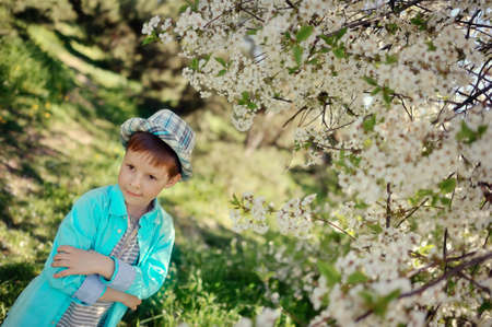 in nature in a lush garden a little boy in a blue shirt and hatの写真素材