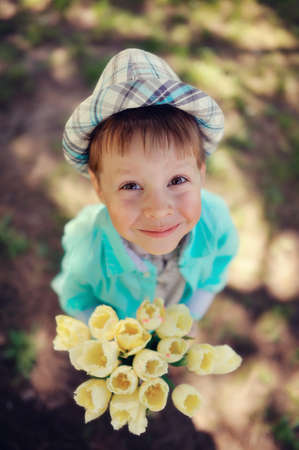 on the nature of the little boy in a blue shirt with a bouquet of white tulipsの写真素材