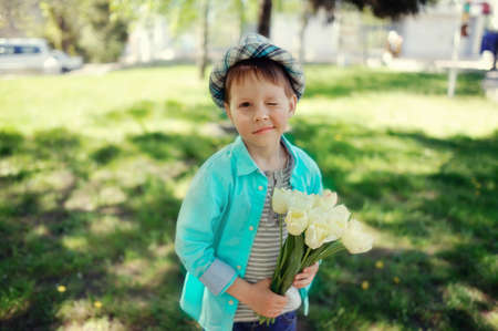 on the nature of the little boy in a blue shirt with a bouquet of white tulipsの写真素材