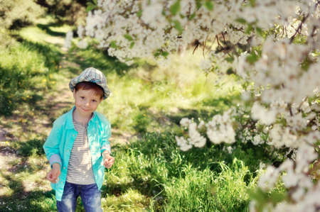 in nature in a lush garden a little boy in a blue shirt and hatの写真素材