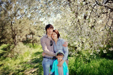 beautiful happy family in the spring in a white flowered garden