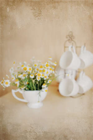 on a beige background white cup on a stand, and one with a bouquet of daisiesの写真素材