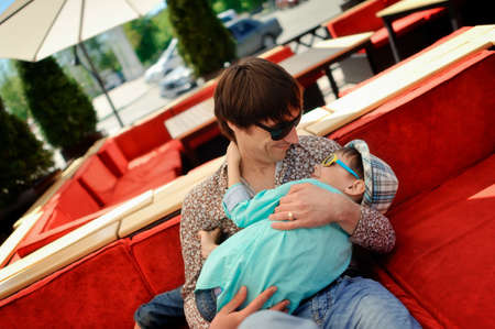 sitting on a red couch and dad holding his son in the Hat