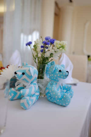 on a white table with a vase of wildflowers sitting teddy bears blue fabricの写真素材
