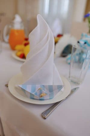 close-up on a background of a banquet table plate with white napkin and paper boatsの写真素材