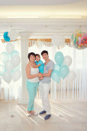 happy family in turquoise costumes against the backdrop of balloonsの写真素材