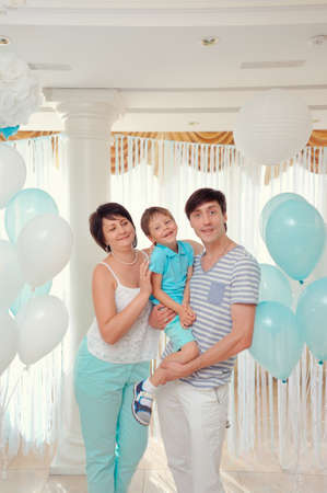happy family in turquoise costumes against the backdrop of balloonsの写真素材