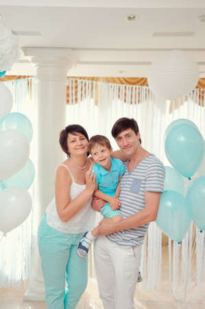 happy family in turquoise costumes against the backdrop of balloonsの写真素材