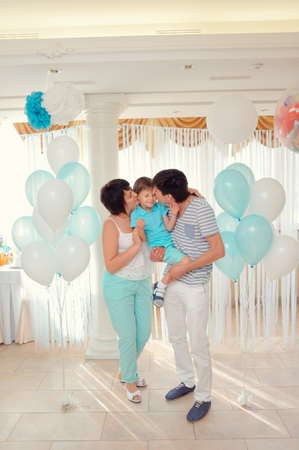 happy family in turquoise costumes against the backdrop of balloonsの写真素材