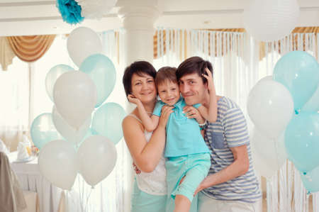 happy family in turquoise costumes against the backdrop of balloonsの写真素材