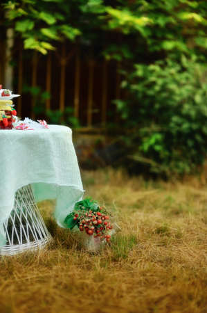 Outdoors on a white table with strawberry jam jars on the grass vase with a bouquetの写真素材