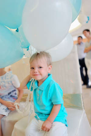 little boy in a blue jacket with big balloonsの写真素材