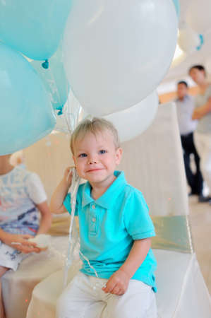 little boy in a blue jacket with big balloonsの写真素材