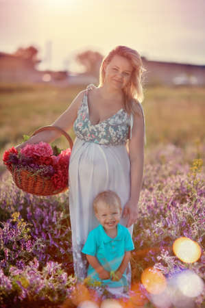 Summer walk on the field with wildflowers pregnant mother with a young sonの写真素材