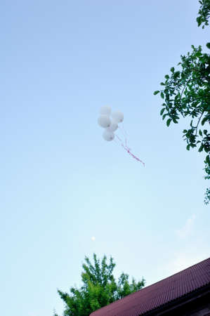 high in the sky flying a bunch of white balloonsの写真素材