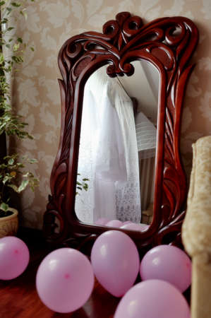 large wall mirror in a wooden frame and balloons on the floorの写真素材