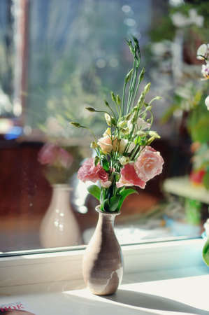 on the window sill is a bouquet of pink roses in a beautiful decorative vaseの写真素材