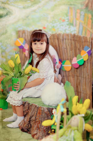 Easter composition of a little girl in a white dress with a rabbit and flowersの写真素材