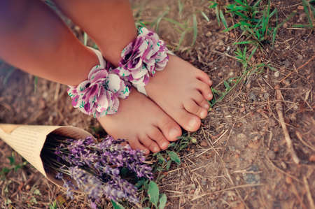 on the ground are bare baby feet and a bouquet of lavenderの写真素材