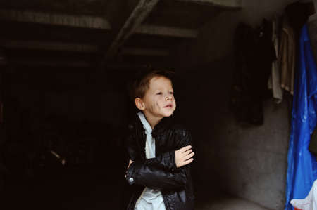 portrait of a mischievous boy with a dirty face in a black jacketの写真素材