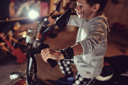 in the garage of a boy with dirty face and stylish hairstyle on a mopedの写真素材