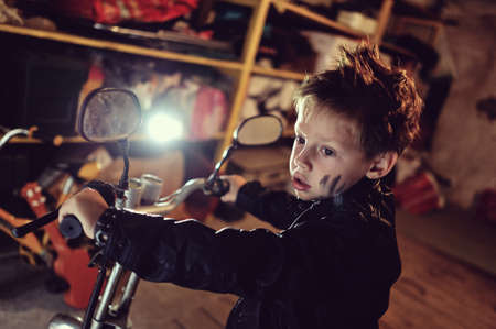 in the garage of a boy in a black jacket with a dirty face on a mopedの写真素材