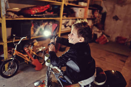 in the garage of a boy in a black jacket with a dirty face on a mopedの写真素材