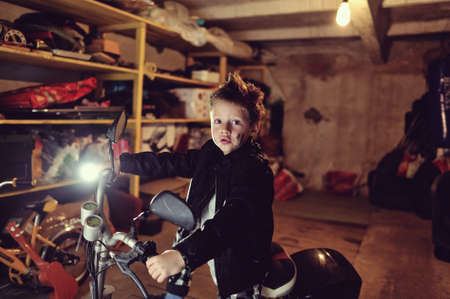 in the garage of a boy in a black jacket with a dirty face on a mopedの写真素材