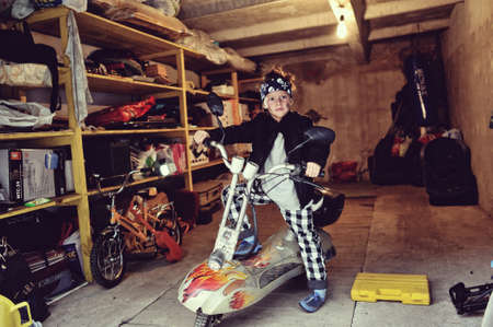 in the garage of a boy in a black jacket with a dirty face on a mopedの写真素材