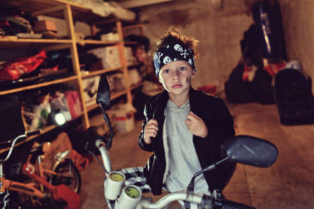in the garage of a boy in a black jacket with a dirty face on a mopedの写真素材
