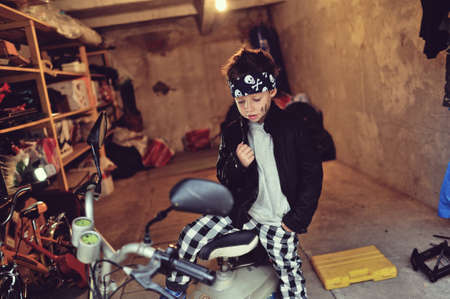 in the garage of a boy in a black jacket with a dirty face on a mopedの写真素材