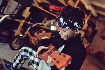 in the garage of a boy with dirty face and a moped with a guitarの写真素材