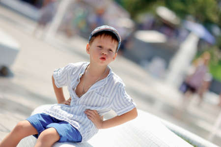 cheerful cute boy in a white shirt and a cap on the streetの写真素材